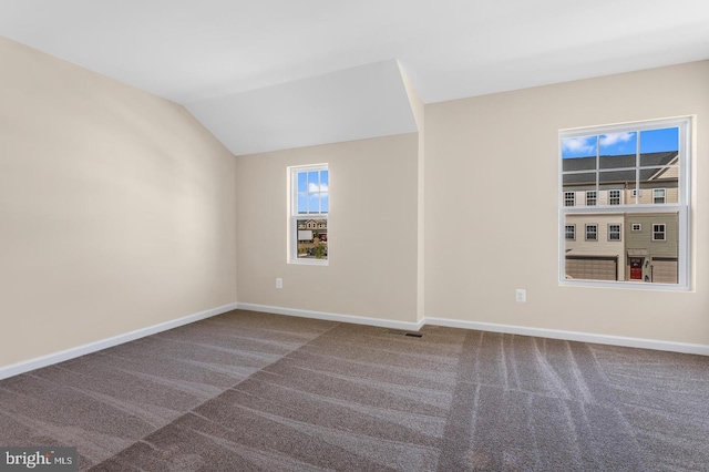 carpeted spare room with vaulted ceiling