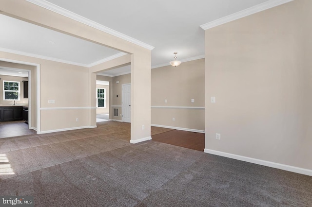 carpeted spare room featuring a healthy amount of sunlight, ornamental molding, and sink