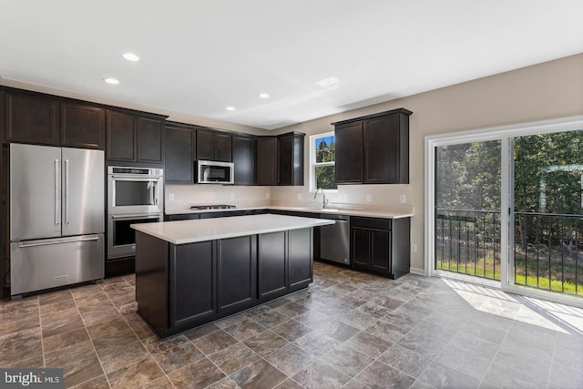 kitchen with appliances with stainless steel finishes, a center island, dark brown cabinets, and sink