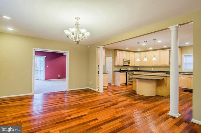 kitchen with appliances with stainless steel finishes, decorative light fixtures, hardwood / wood-style flooring, a notable chandelier, and a center island