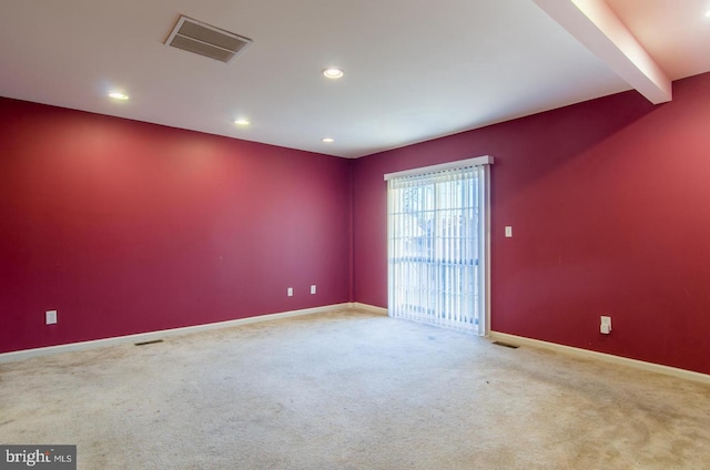 spare room with carpet flooring and beamed ceiling