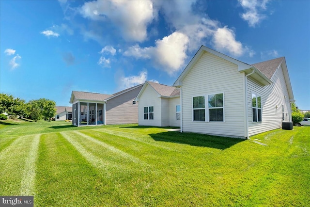 back of house with a sunroom, a lawn, and central AC