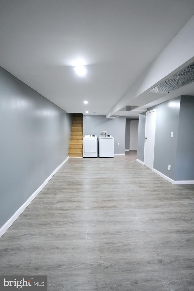 basement featuring light wood-type flooring and separate washer and dryer