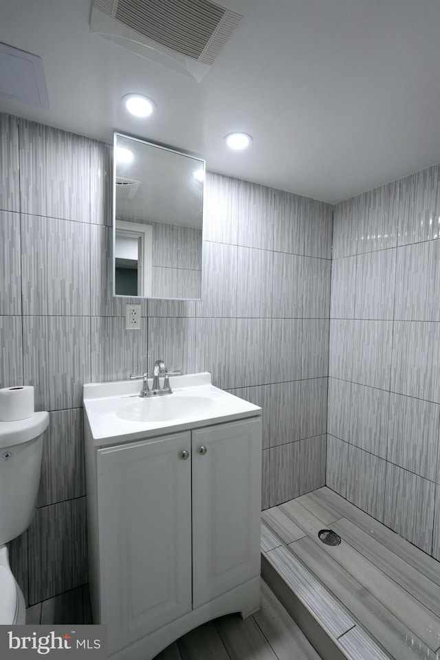 bathroom featuring vanity, tile patterned floors, toilet, tile walls, and walk in shower