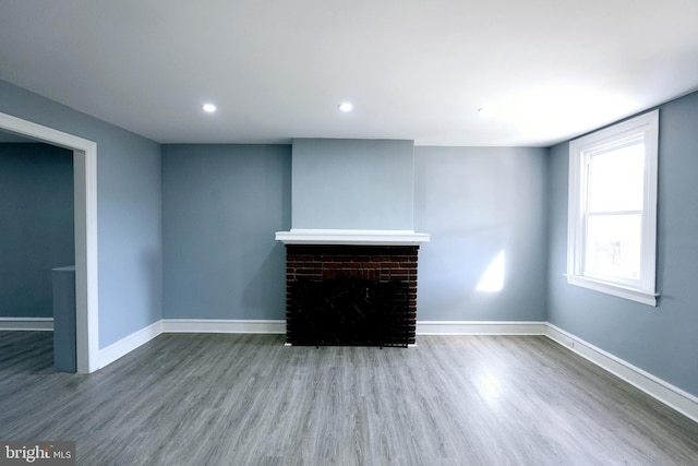 unfurnished living room with hardwood / wood-style flooring and a brick fireplace