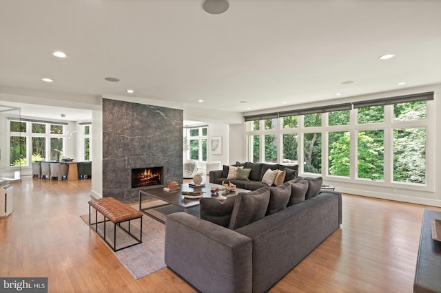 living room featuring light wood-style floors, a wealth of natural light, a fireplace, and recessed lighting