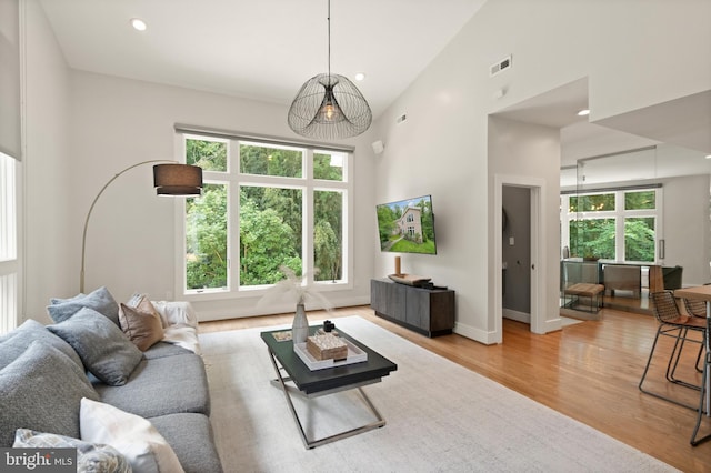 living area with baseboards, visible vents, light wood-type flooring, high vaulted ceiling, and recessed lighting