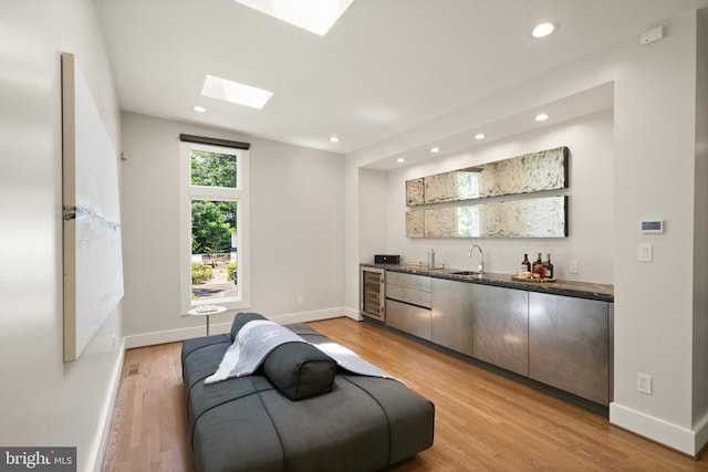 bar featuring baseboards, wet bar, light wood-type flooring, and recessed lighting