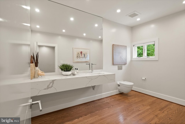 bathroom featuring toilet, recessed lighting, wood finished floors, visible vents, and a sink