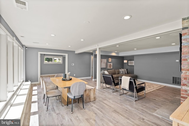 dining area with light wood-type flooring, visible vents, and baseboards