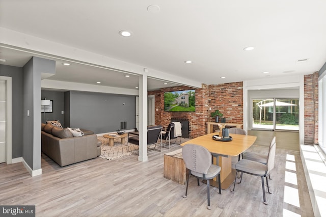 dining area featuring baseboards, brick wall, light wood-style flooring, a fireplace, and recessed lighting