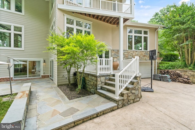 doorway to property with concrete driveway, a patio, a balcony, and stucco siding