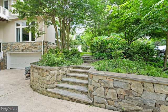 view of yard featuring driveway, an attached garage, and a balcony