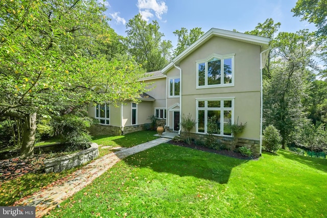 view of front facade featuring stone siding, stucco siding, and a front yard