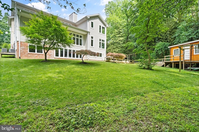 back of property with brick siding, a yard, and a chimney