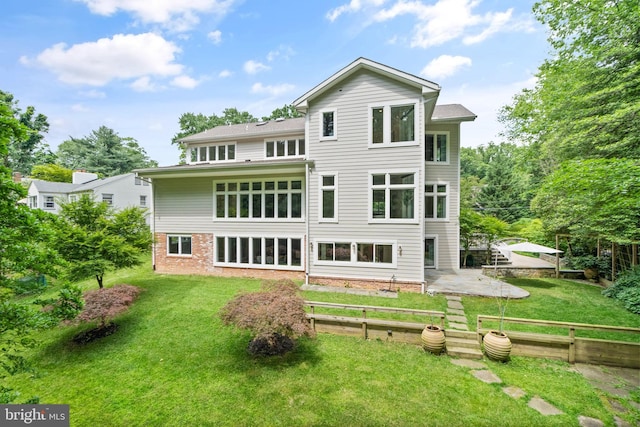 back of house featuring a yard, a garden, brick siding, and a patio