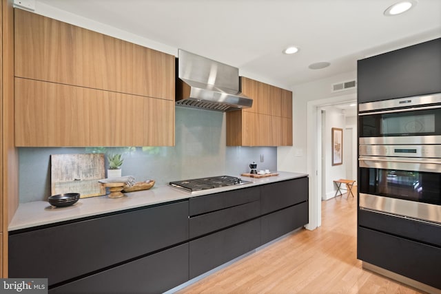 kitchen with visible vents, wall chimney exhaust hood, modern cabinets, light countertops, and stainless steel appliances