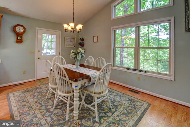 dining room with light hardwood / wood-style floors, lofted ceiling, and an inviting chandelier