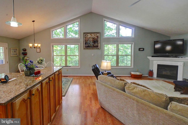 living room with a chandelier, light hardwood / wood-style floors, and vaulted ceiling