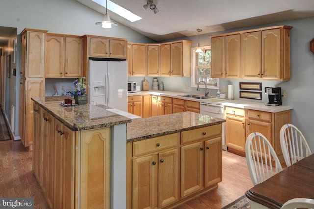 kitchen with a center island, sink, white appliances, and hanging light fixtures