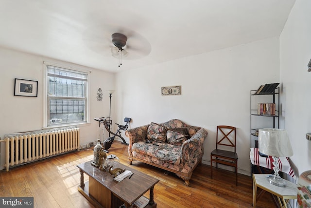 living room featuring hardwood / wood-style floors, baseboard heating, radiator, and ceiling fan