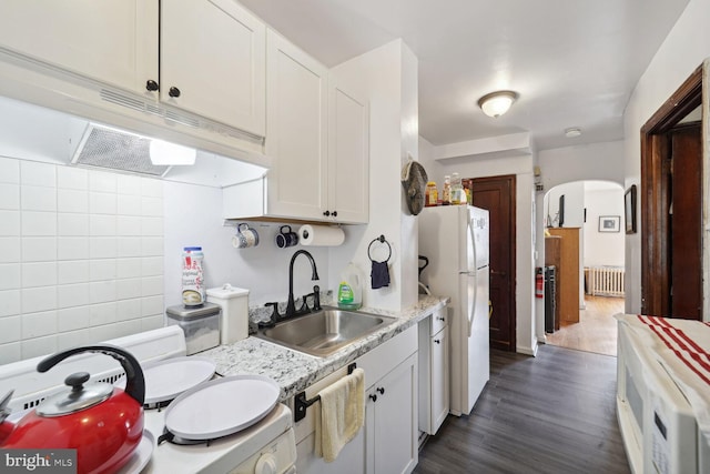 kitchen with radiator, sink, dark hardwood / wood-style floors, white refrigerator, and white cabinets