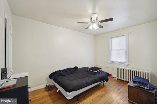 bedroom featuring hardwood / wood-style floors, ceiling fan, and radiator heating unit