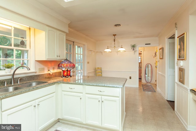 kitchen with sink, crown molding, hanging light fixtures, kitchen peninsula, and white cabinets