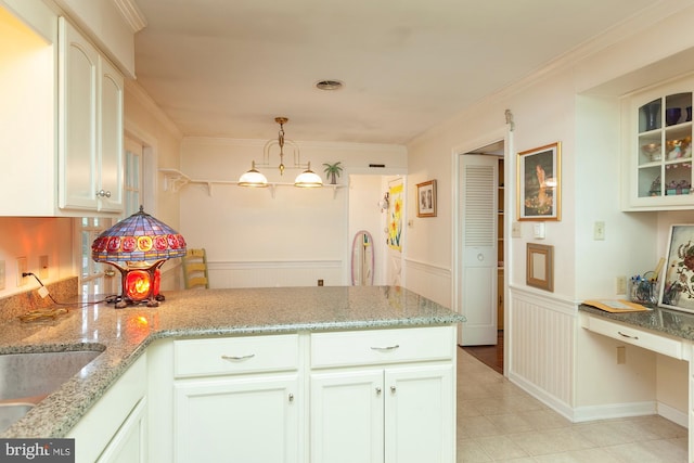 kitchen with white cabinetry, ornamental molding, pendant lighting, and light stone counters