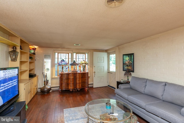 living room featuring a baseboard heating unit, brick wall, dark wood-type flooring, and a textured ceiling