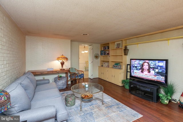 living room featuring brick wall, dark wood-type flooring, and a textured ceiling