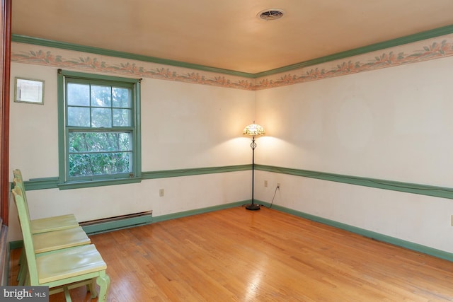 empty room featuring a baseboard radiator and light hardwood / wood-style floors