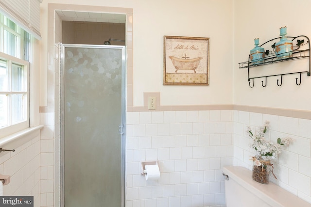 bathroom featuring a shower with shower door, tile walls, and toilet