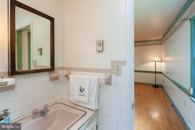 bathroom featuring crown molding, sink, hardwood / wood-style floors, and tile walls