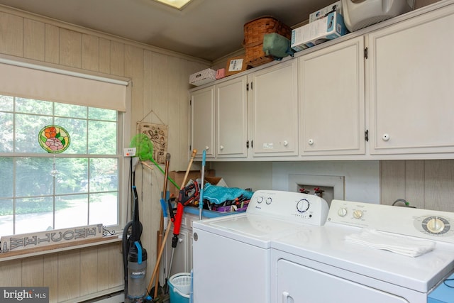 washroom with cabinets, a healthy amount of sunlight, separate washer and dryer, and wood walls