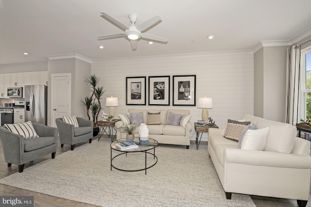 living room with light wood finished floors, ornamental molding, a ceiling fan, and recessed lighting