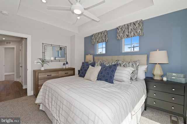 bedroom with a raised ceiling, ceiling fan, and carpet