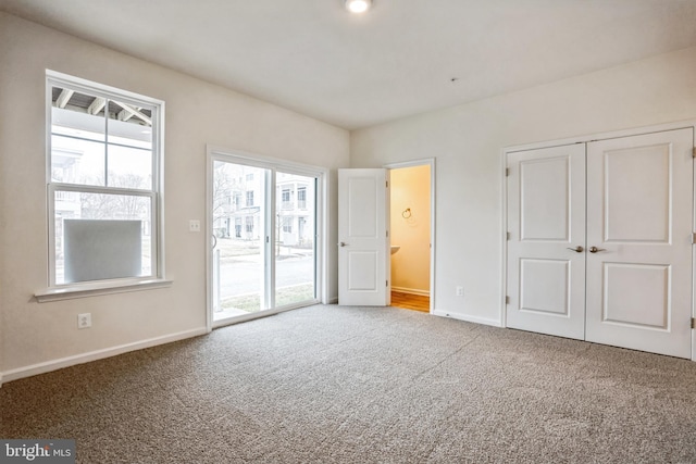 unfurnished bedroom featuring access to outside, a closet, carpet flooring, and baseboards