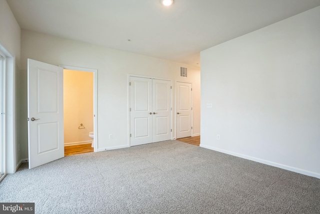 unfurnished bedroom featuring carpet floors, a closet, visible vents, connected bathroom, and baseboards