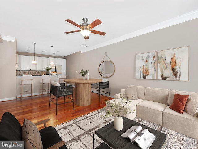 living room with hardwood / wood-style flooring, ceiling fan, and crown molding