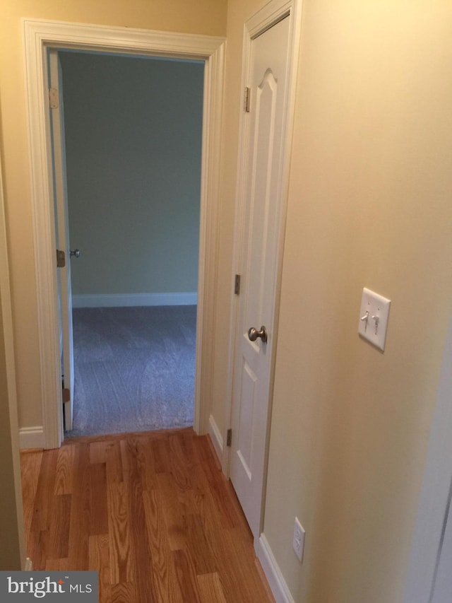 hall featuring light wood-type flooring and baseboards