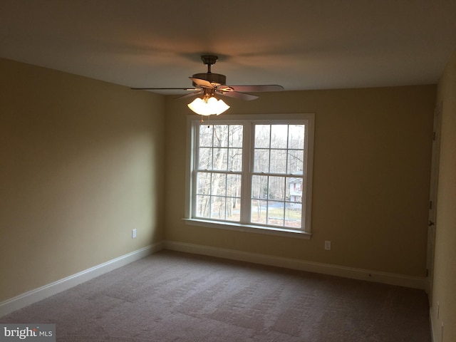 carpeted spare room featuring a ceiling fan and baseboards