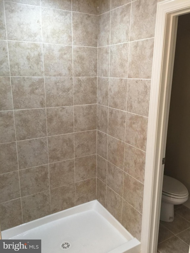 full bath featuring a stall shower, toilet, and tile patterned floors