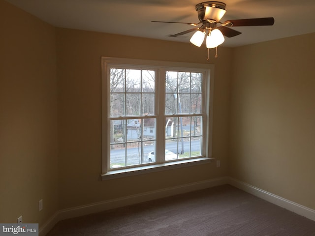 carpeted spare room featuring ceiling fan and baseboards