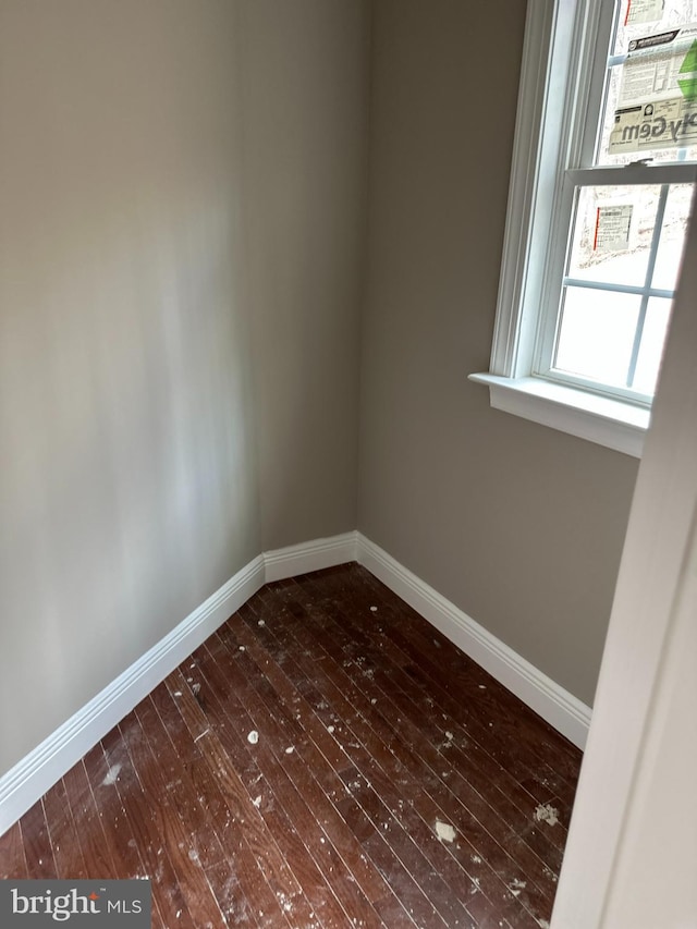 empty room with baseboards and dark wood-type flooring