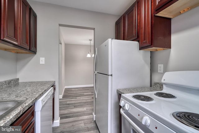 kitchen featuring decorative light fixtures, white appliances, light hardwood / wood-style floors, and sink