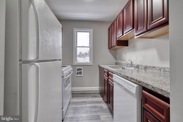 kitchen featuring heating unit, sink, light hardwood / wood-style floors, and white appliances