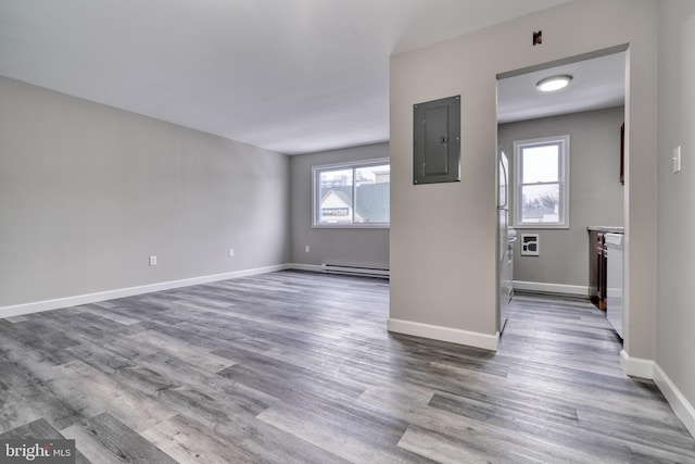 unfurnished living room with hardwood / wood-style floors, plenty of natural light, baseboard heating, and electric panel