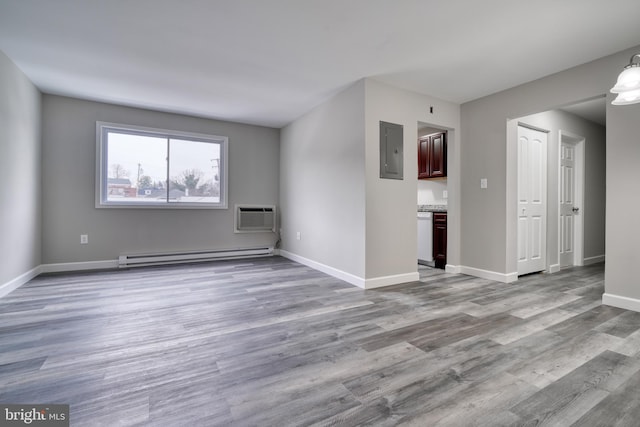 unfurnished room featuring a wall mounted AC, light wood-type flooring, electric panel, and baseboard heating