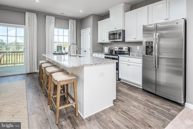 kitchen featuring appliances with stainless steel finishes, white cabinets, a kitchen island with sink, and plenty of natural light